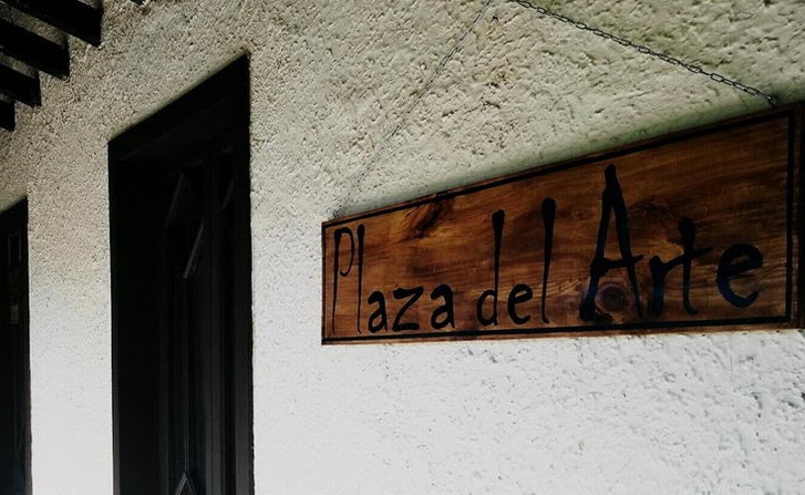 Letrero de madera tallado con el nombre Plaza del Arte, en el muro de la casa